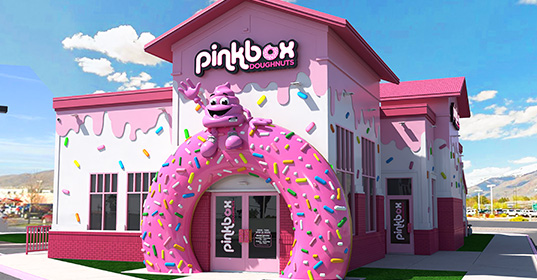 Pinkbox Doughnuts storefront with oversized pink donut entrance and playful exterior design.